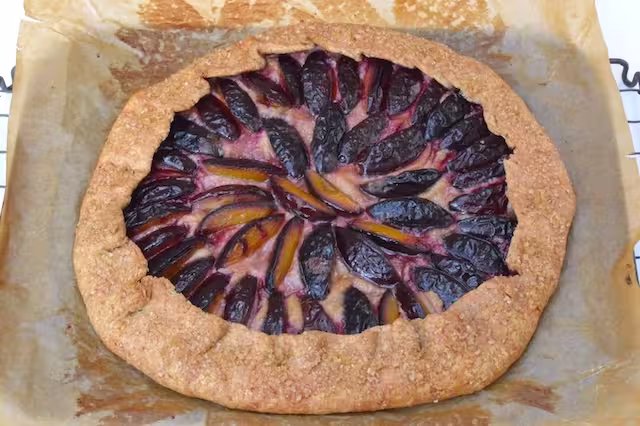 Baked plum galette on baking tray just out of the oven.