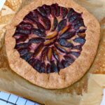 Plum ricotta galette with wholemeal spelt flaky pastry cooling on baking paper and wire rack.