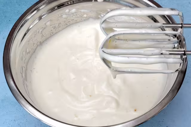 Whisked eggs and sugar in bowl with beaters.