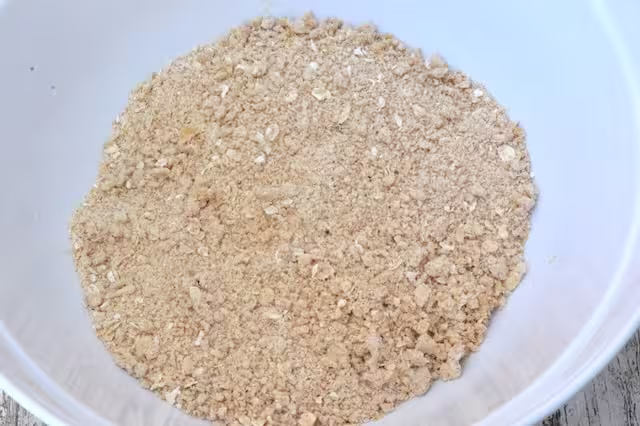 Bowl of butter rubbed into flour and oats to resemble breadcrumbs.