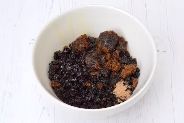 Currants, rum, sugar and nutmeg in a small pudding bowl.