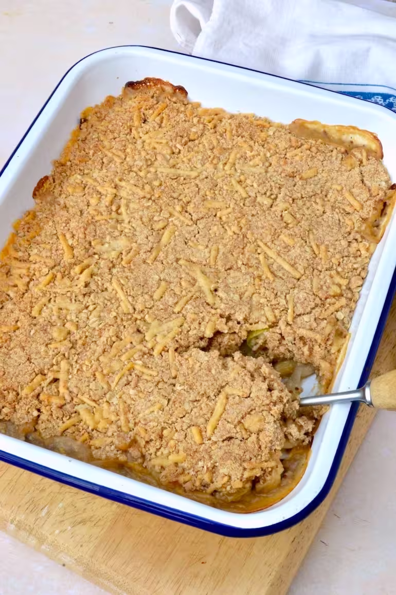 Spoon inserted into cheesy leek and bean crumble.