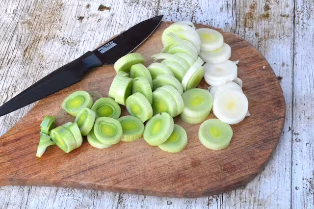 Leeks sliced into rings on board with knife.