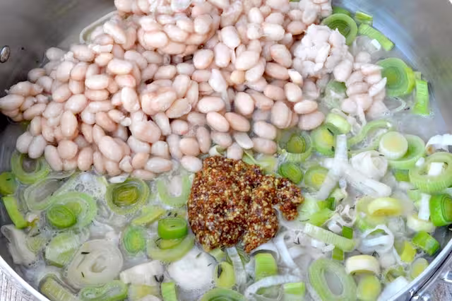 Mustard, beans and stock added to pan of leeks.