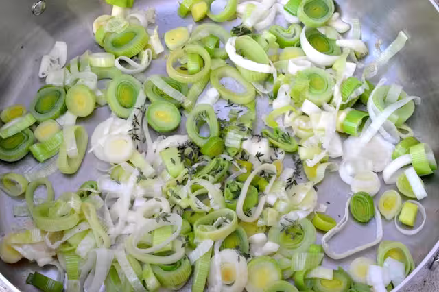 Thyme leaves added to pan of frying leeks.